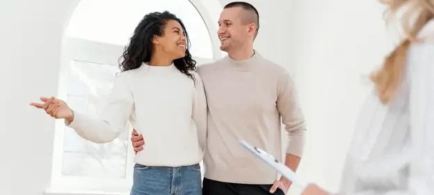 New Homeowners smiling at each other with open arms