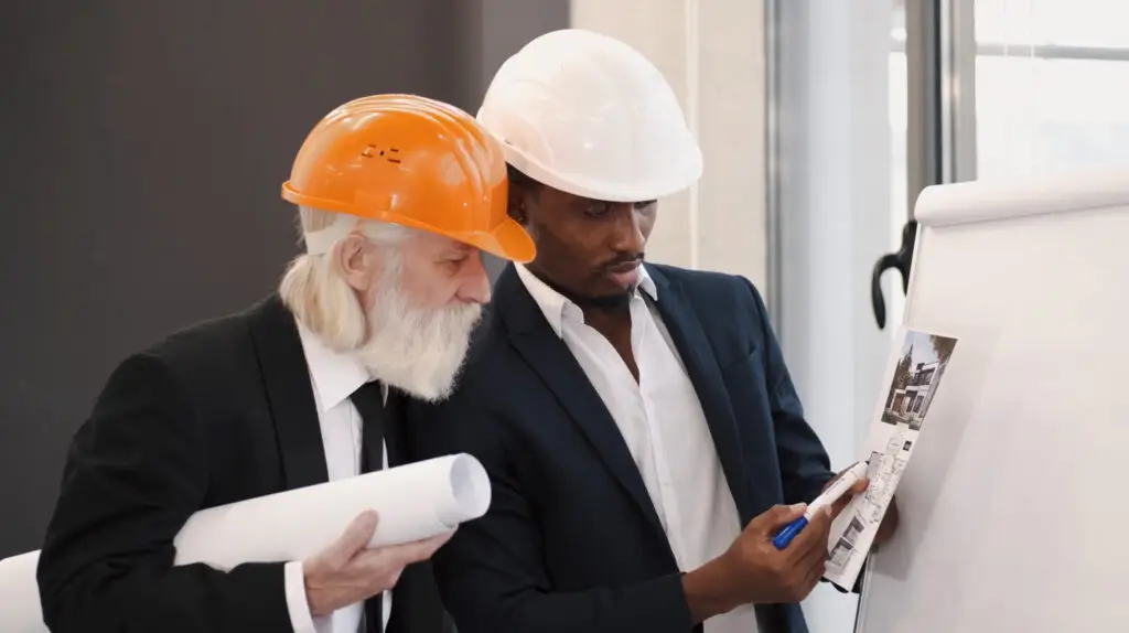 senior man looking at house plans with hard hat on